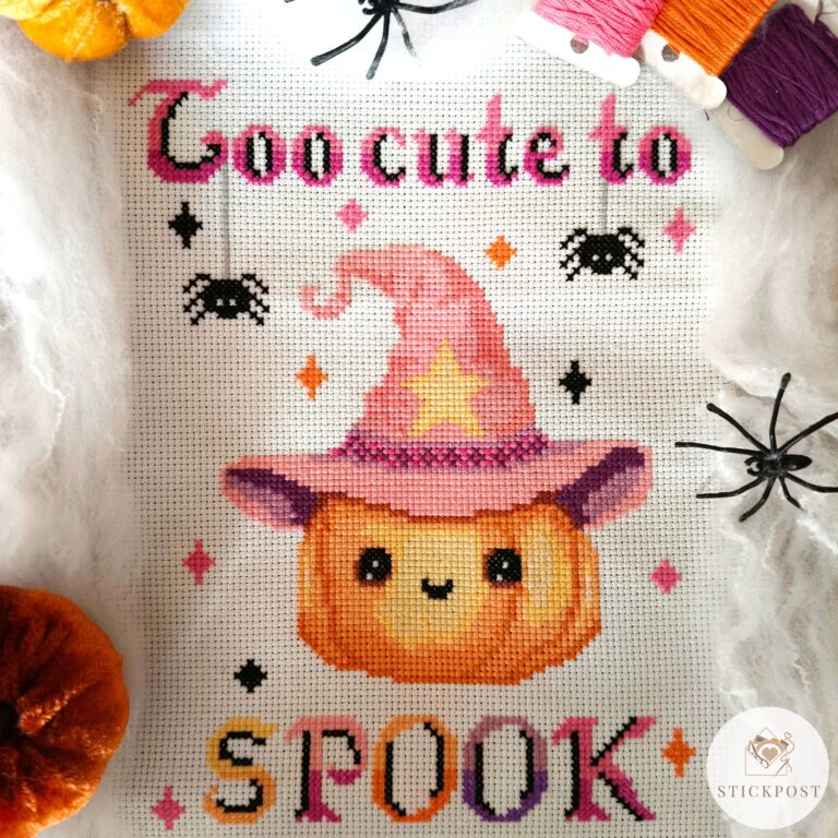 Kreuzstich Vorlagen Kürbis mit rosafarbenen Hexenhut umrandet von bunten Funkelsternen. Über dem Kürbis steht der Schriftzug Too cute to in rosa und schwarz mit zwei sich abseilenden Spinnen. Unter dem Kürbis steht in Großbuchstaben SPOOK in bunten Farben und schwarzen Schatten. Auf dem Bild ist ein Hinweis Button das es sich um eine PDF Vorlage handelt.