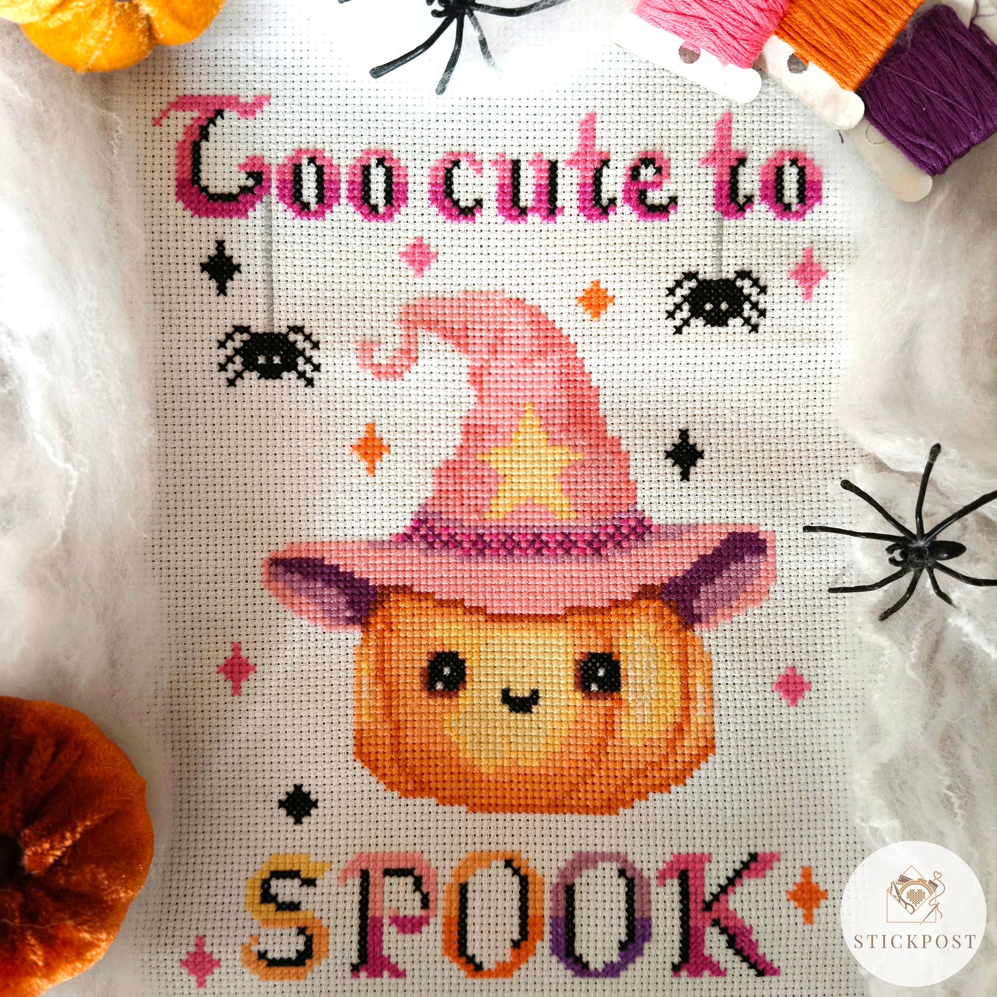 Kreuzstich Vorlagen Magic Pumpkin Stickpost Shop Kreuzstich Vorlagen Kürbis mit rosafarbenen Hexenhut umrandet von bunten Funkelsternen. Über dem Kürbis steht der Schriftzug Too cute to in rosa und schwarz mit zwei sich abseilenden Spinnen. Unter dem Kürbis steht in Großbuchstaben SPOOK in bunten Farben und schwarzen Schatten. Auf dem Bild ist ein Hinweis Button das es sich um eine PDF Vorlage handelt.