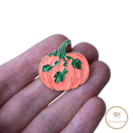 Herbstkürbis Nadelmagnet. orangefarbener Kürbis mit grünen Blätterranken. Nadelmagnet liegt auf einer Hand um das Größenverhältnis darzustellen.