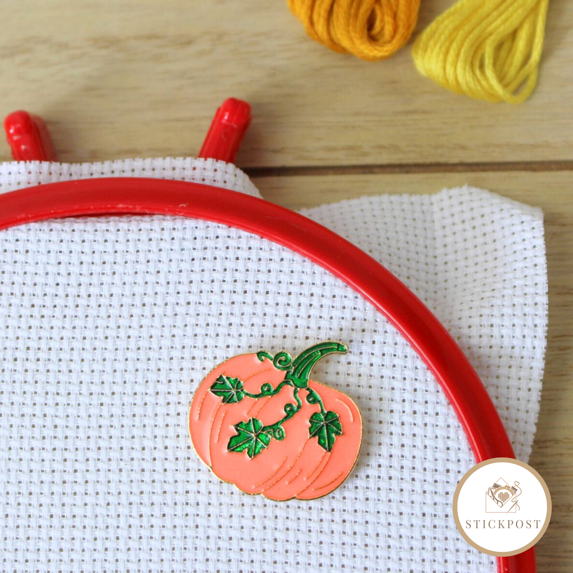 Stickpost Herbstkürbis Nadelmagnet Herbstkürbis Nadelmagnet. orangefarbener Kürbis mit grünen Blätterranken. Magnethalterung auf Stoff im Stickrahmen gezeigt.