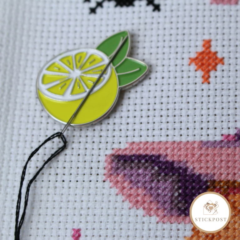 Lemon Love Nadelmagnet. Gelbe aufgeschnittene Zitrone mit grünen Blättern. Angewendet auf einem Stickbild. Zeigt wie die Magnethalterung die Sticknadel hält.
